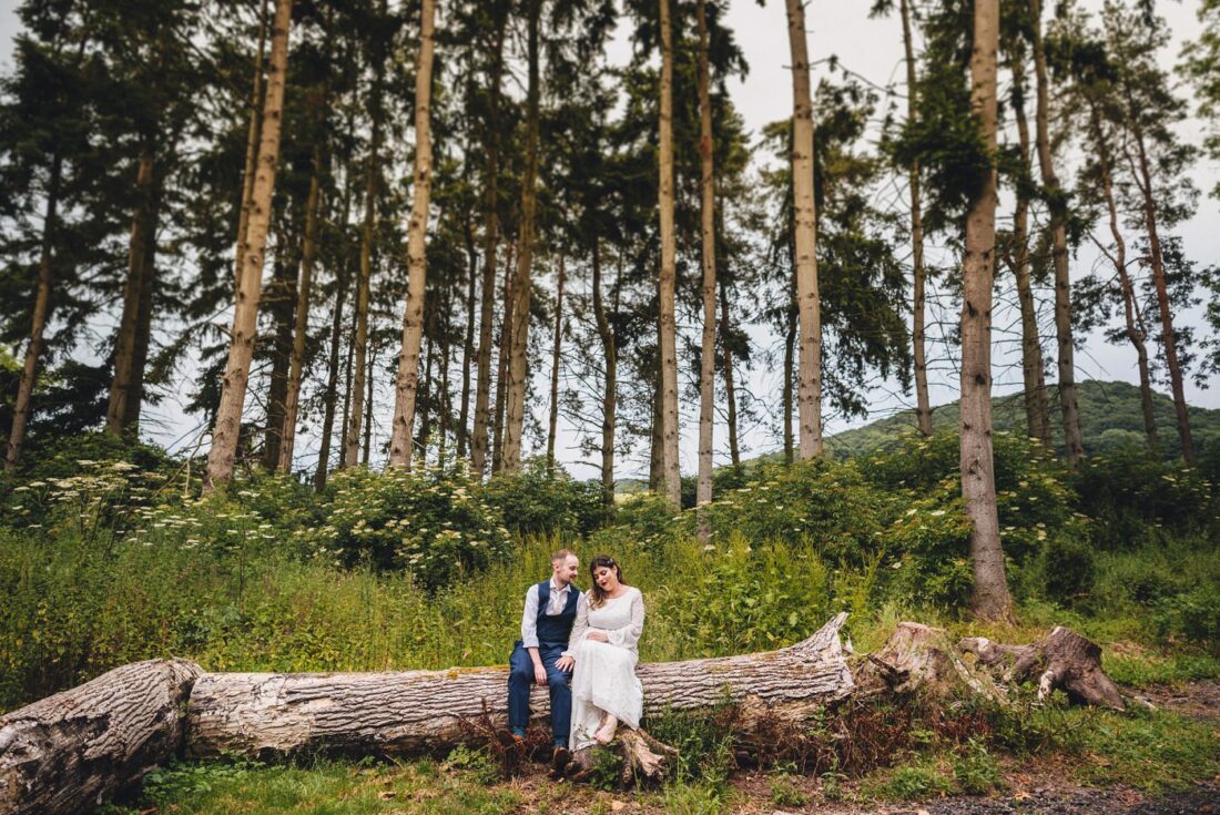 Woodland area at Brinsop Court - couple sitting on a log, enjoying time together just married