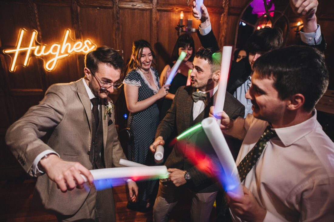 groom dancing with his friends at Deer Park, neon sign on the wall