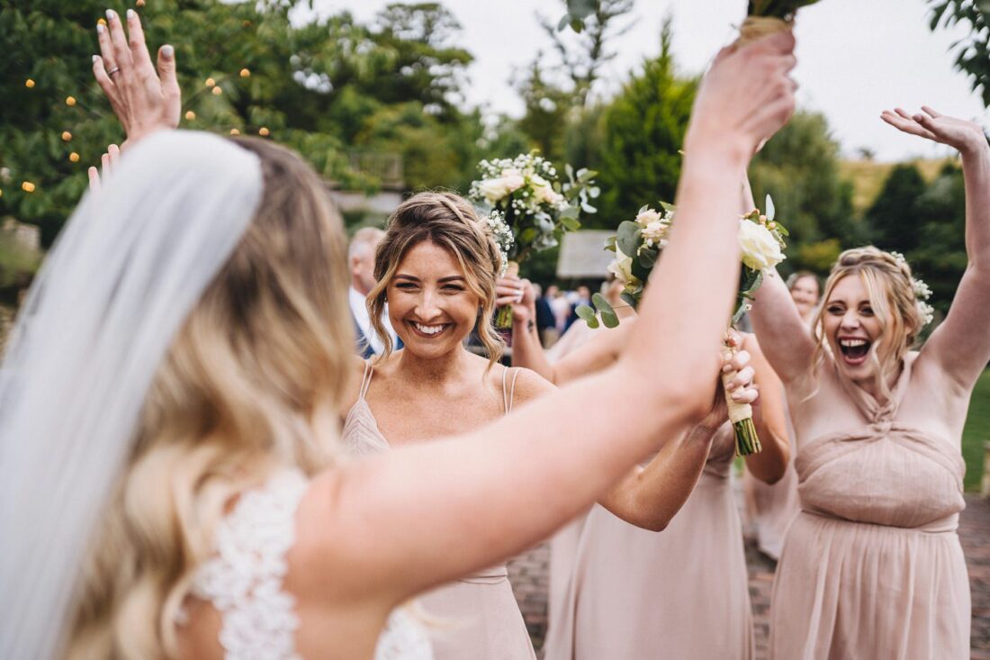 bridesmaids smiling and running to hug the bride