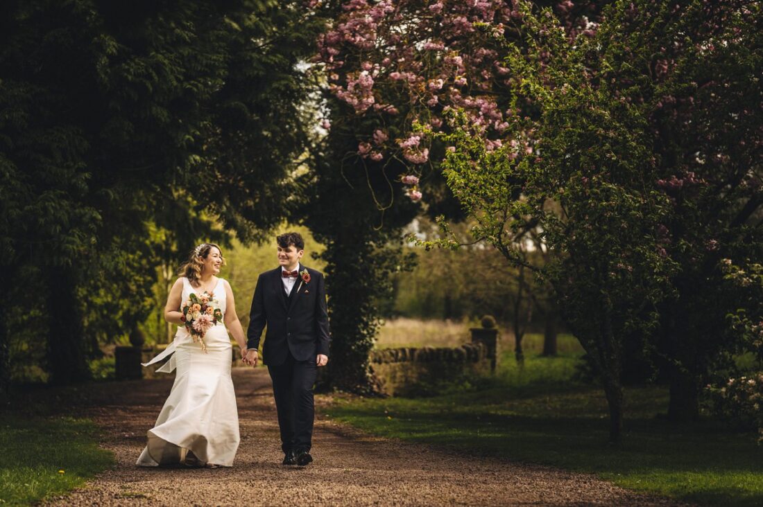 bride and groom walking together holding hands on the Birtsmorton Court grounds in spring