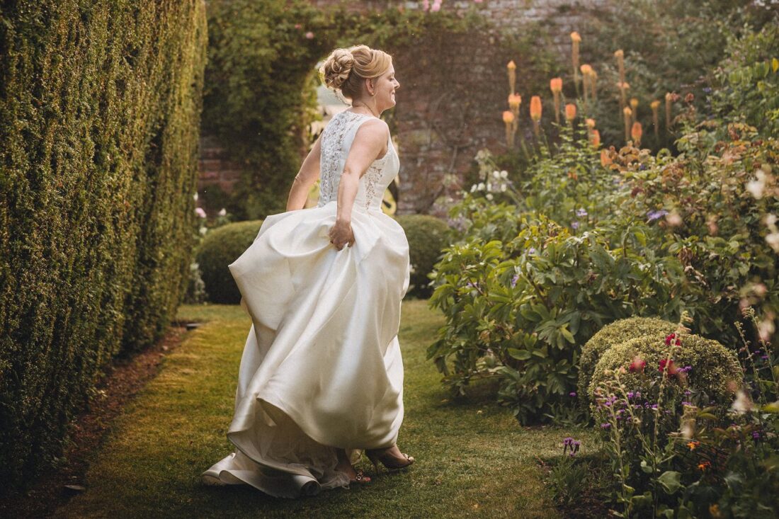 bride dancing among the flowers in the white garden at Birtsmorton Court