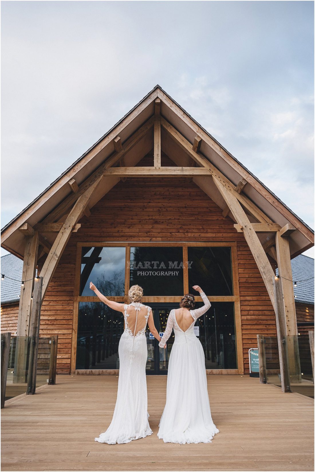 Mill Barns wedding photography two brides going back into the building hands up in the air