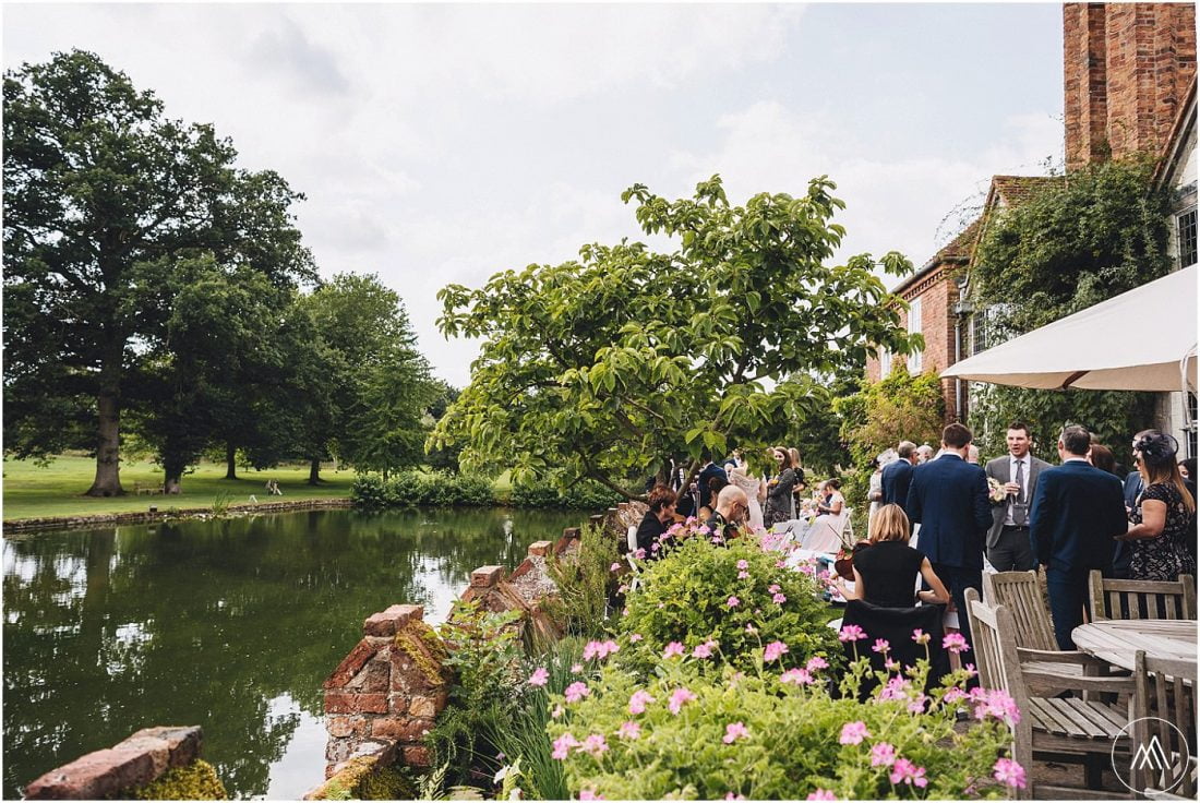 wedding guests enjoying reception drinks and musicians playing on the terrace by the moat