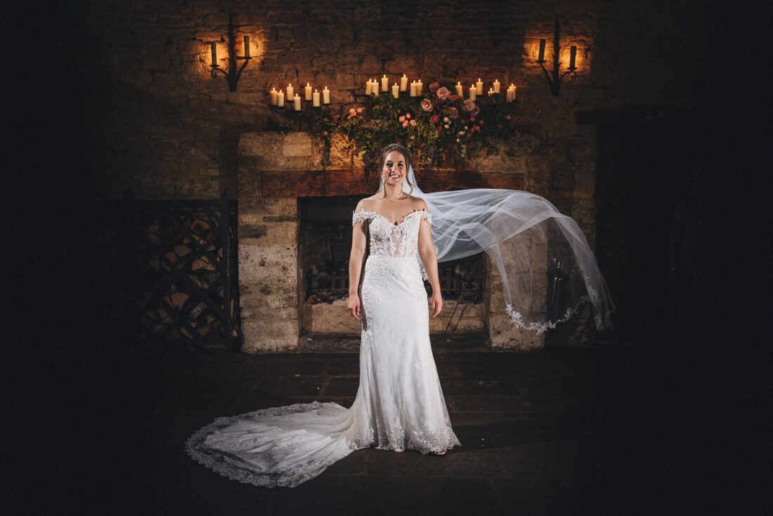 bride at Cripps barn standing in front of a fire place in the ceremony room