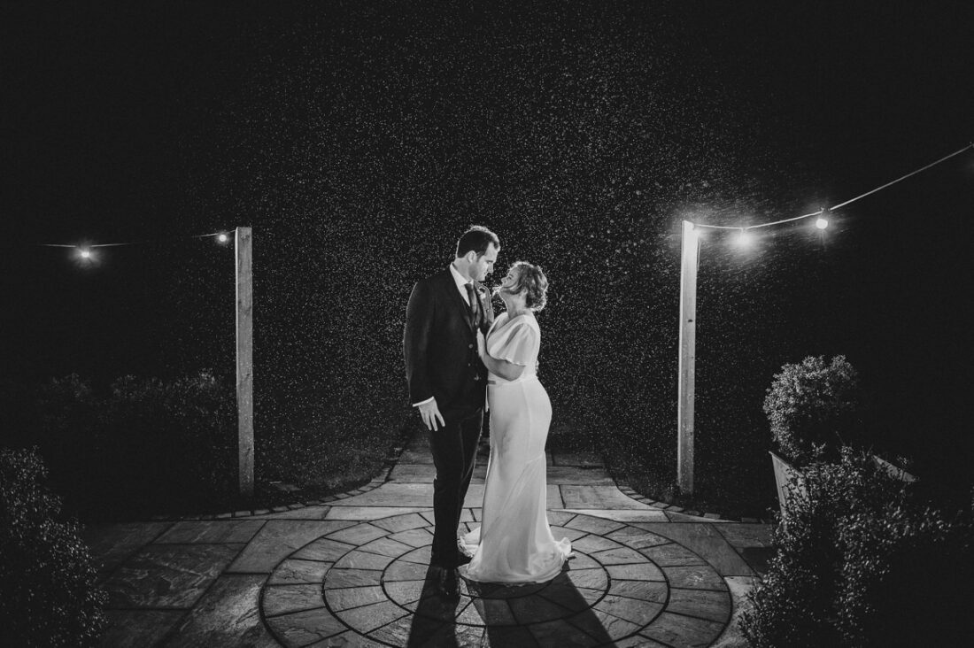 bride and groom posing for the rainy backlit picture at night, rain visible