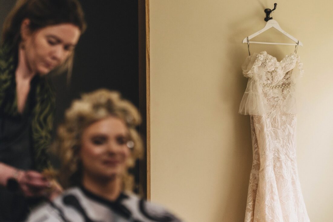 bride having her haid done and dress hanging on the way, getting ready at Bredenbury Court Barns