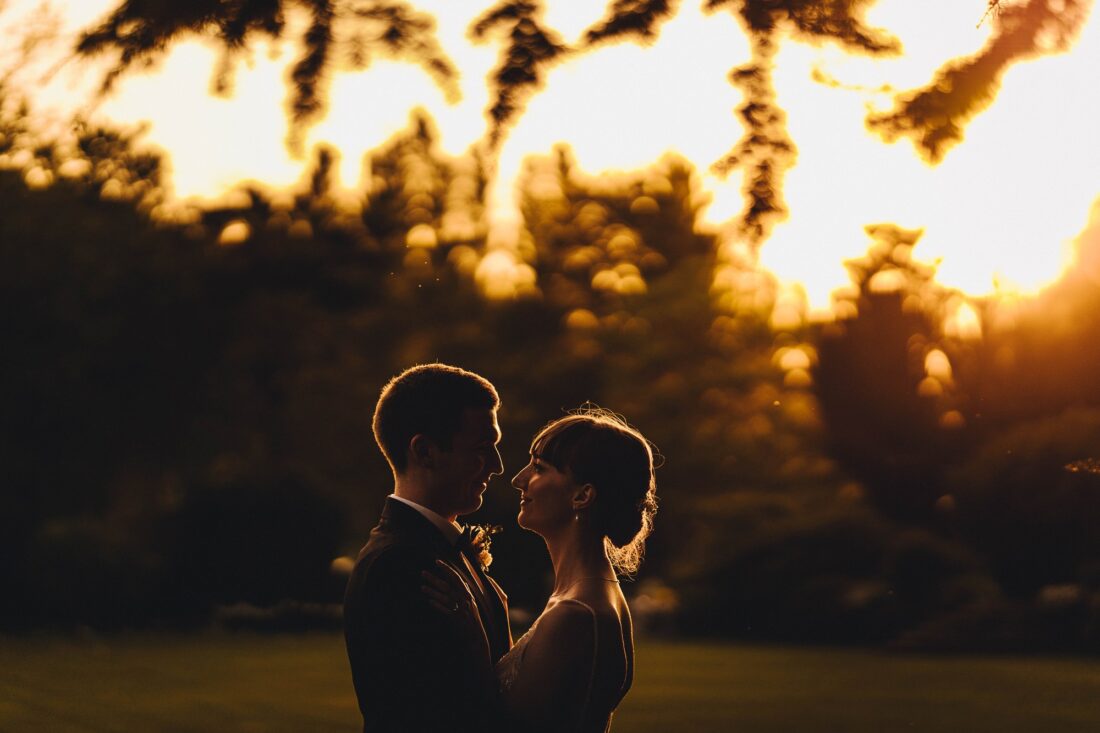 just married couple in the golden hour at Brinsop Court, photo taken at the lawn by the moat