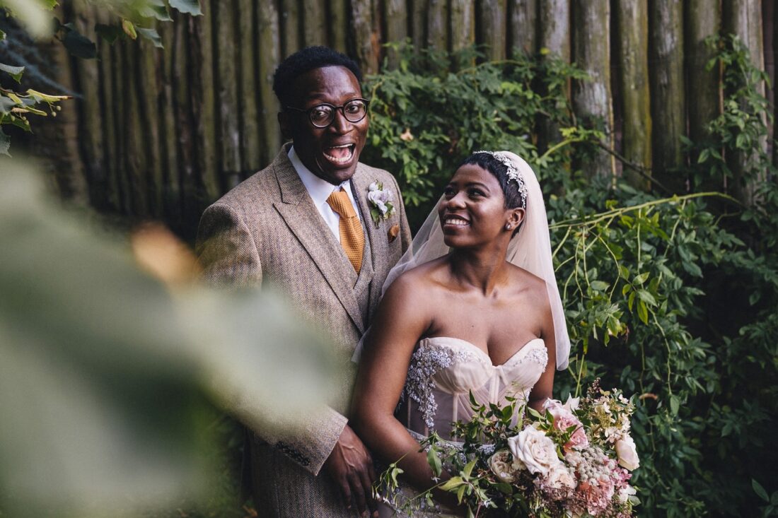 African couple just married and posing in front of the wooden wall at Dewsall Court