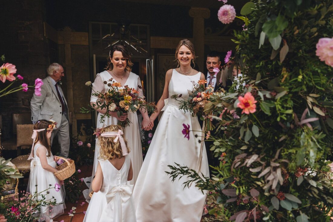 lesbian wedding ceremony in the orangery room at Dewsall Court, flower girls and beautiful floral decorations in the foreground