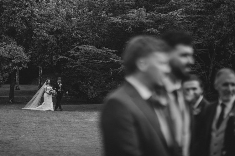 bride on the way to the ceremony by the moat at Birtsmorton Court