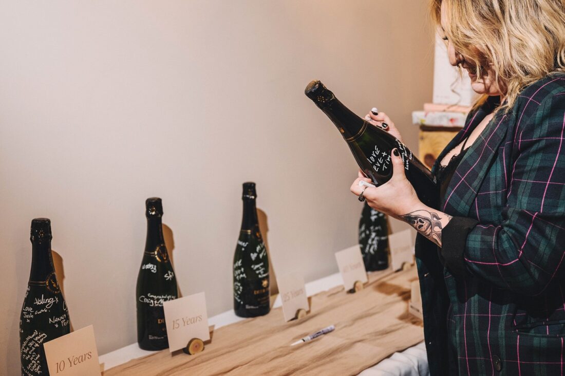 wedding guest signing a wine champagne bottle